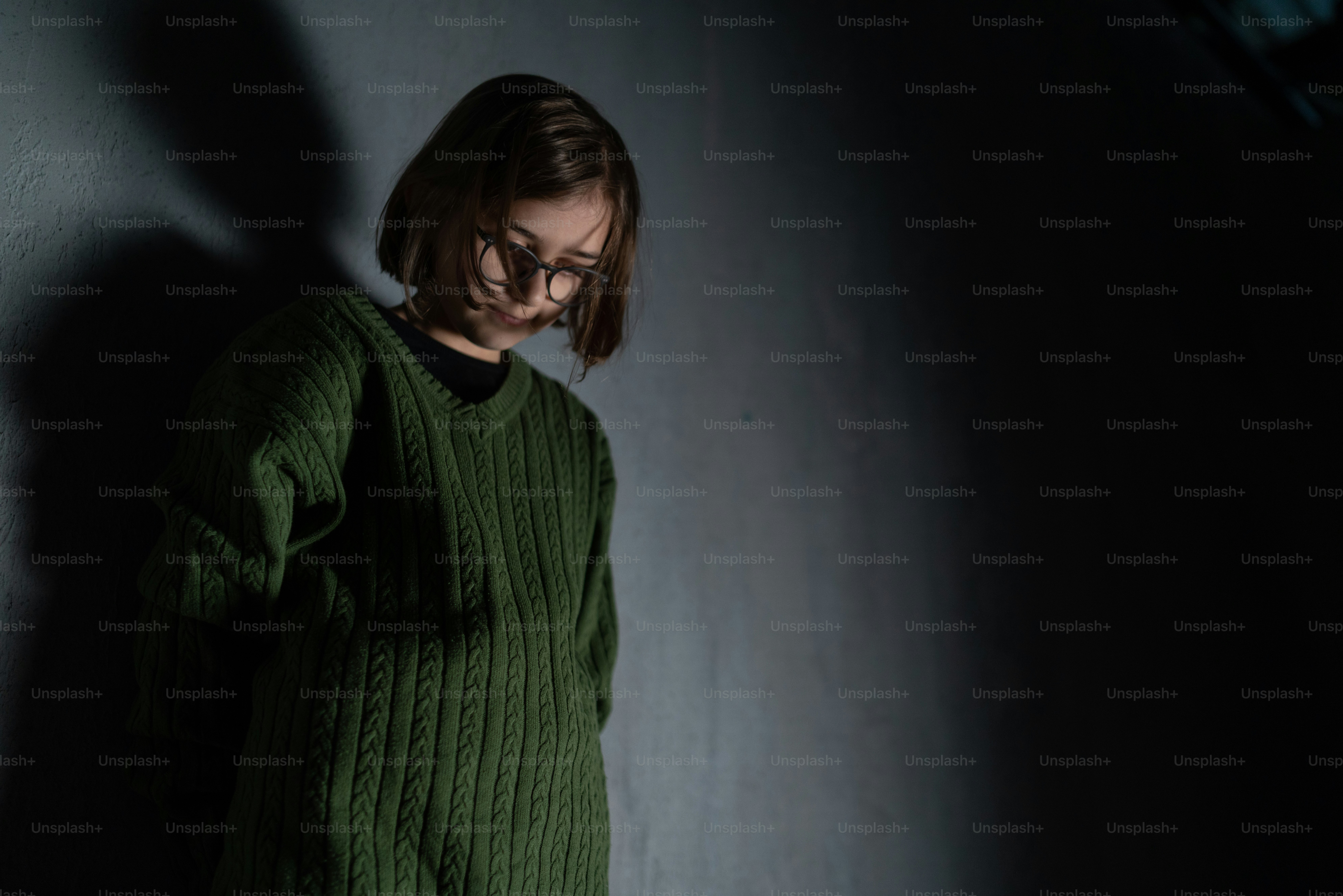 Una bambina triste, sola nell'oscurità, in piedi e pensante.