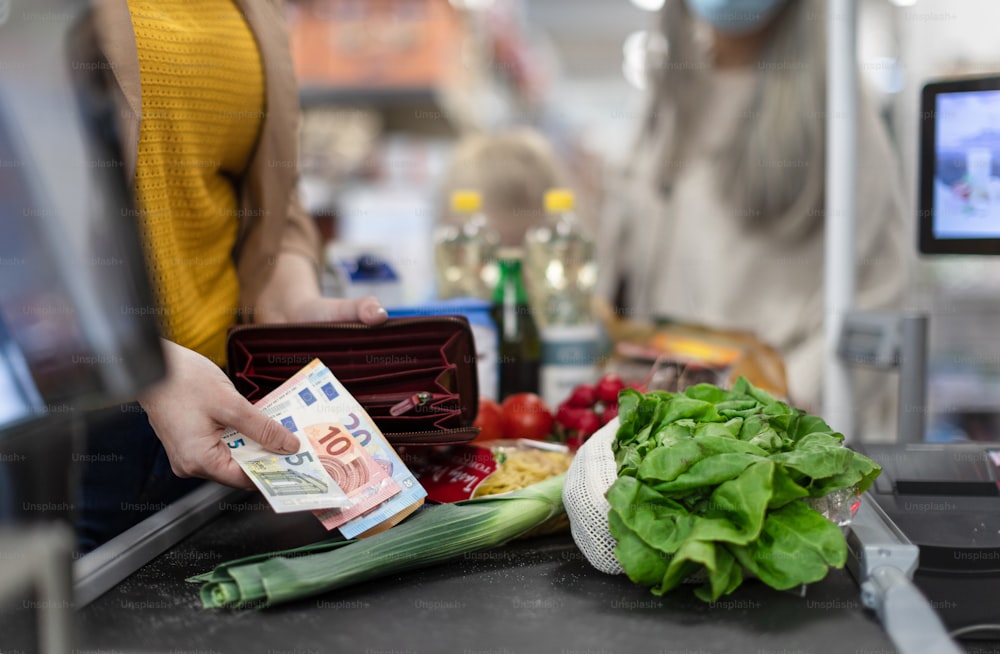 �スーパーマーケットのレジでお金を渡す女性の接写