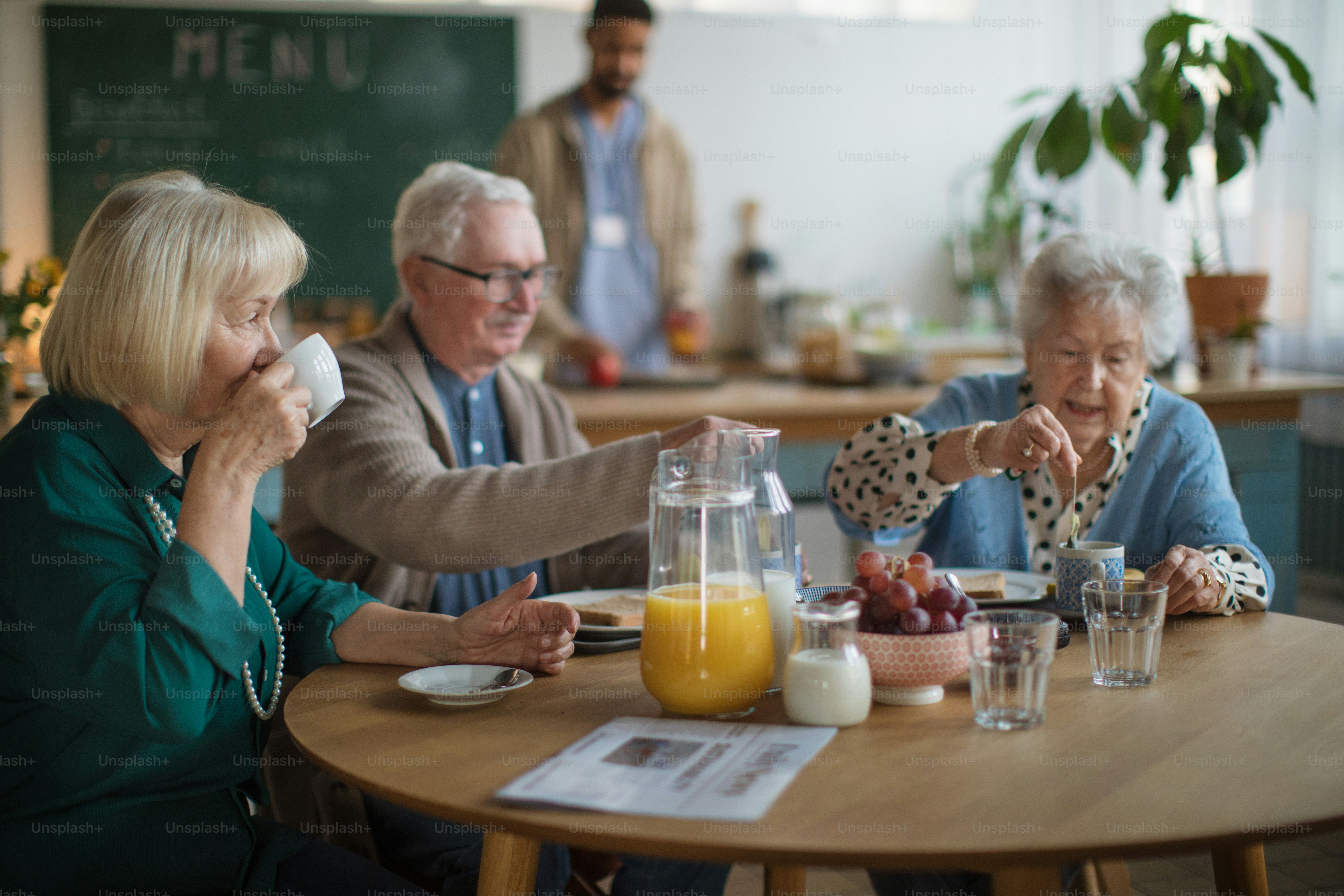 Eine Gruppe fröhlicher Senioren genießt das Frühstück im Pflegeheim.