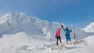スロバキアのロータトラ山脈の山の頂上でハイタッチするスキーツーリングカップル。