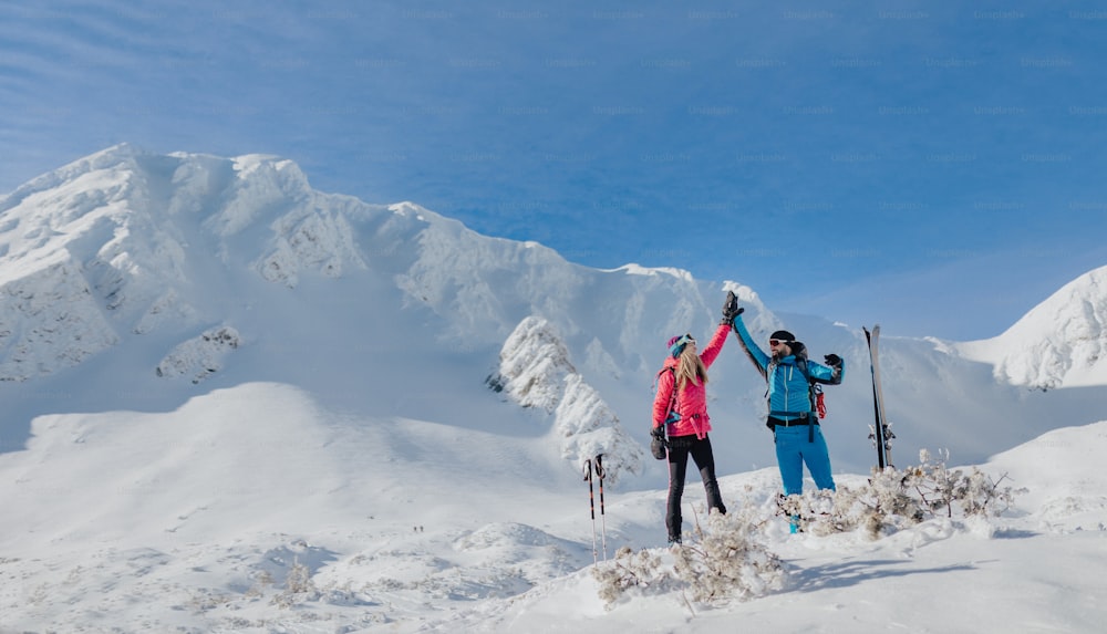 A ski touring couple high fiving on the top of mountain in the Low Tatras in Slovakia.