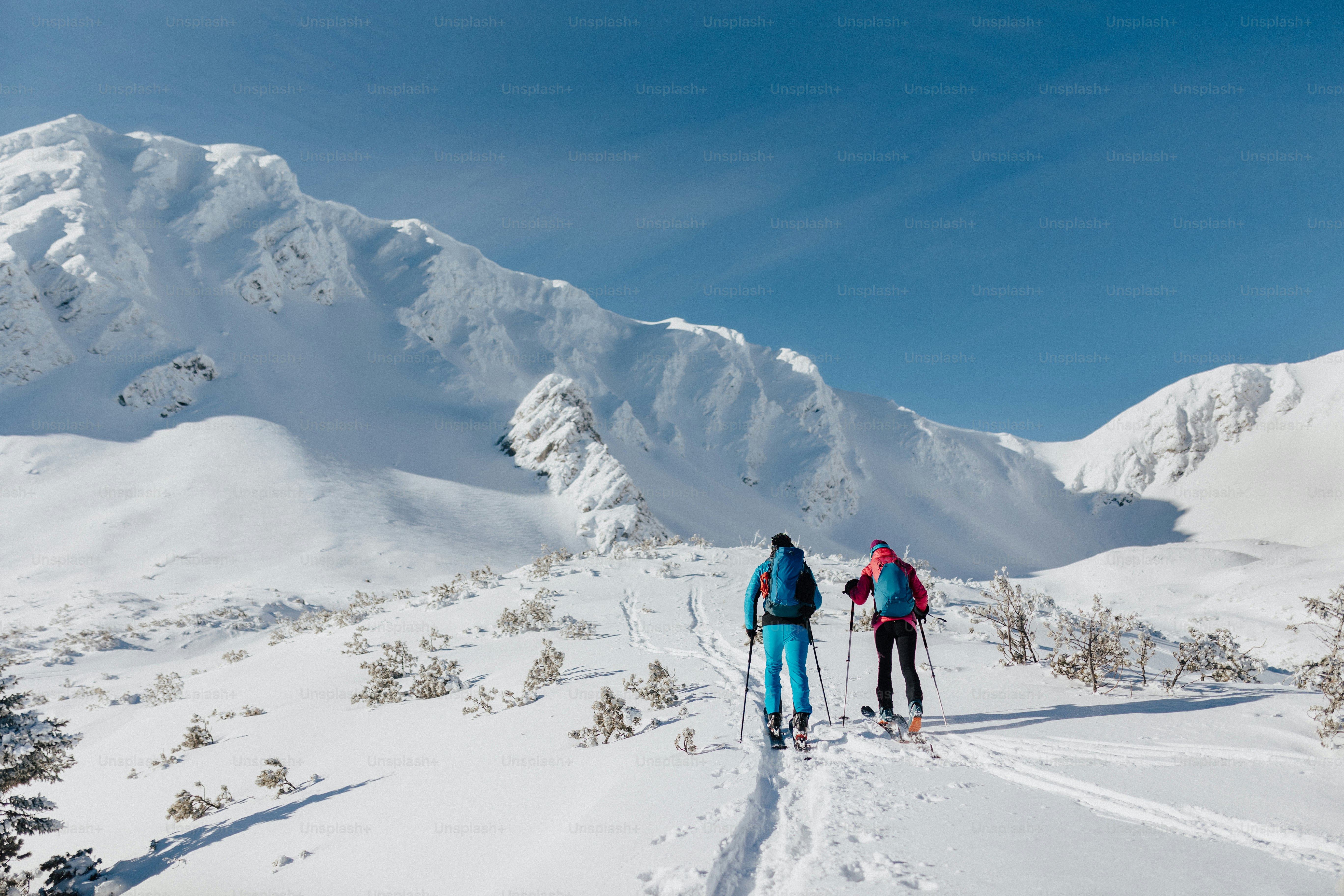 A rear view of ski touring couple hiking up a in the Low Tatras in ...