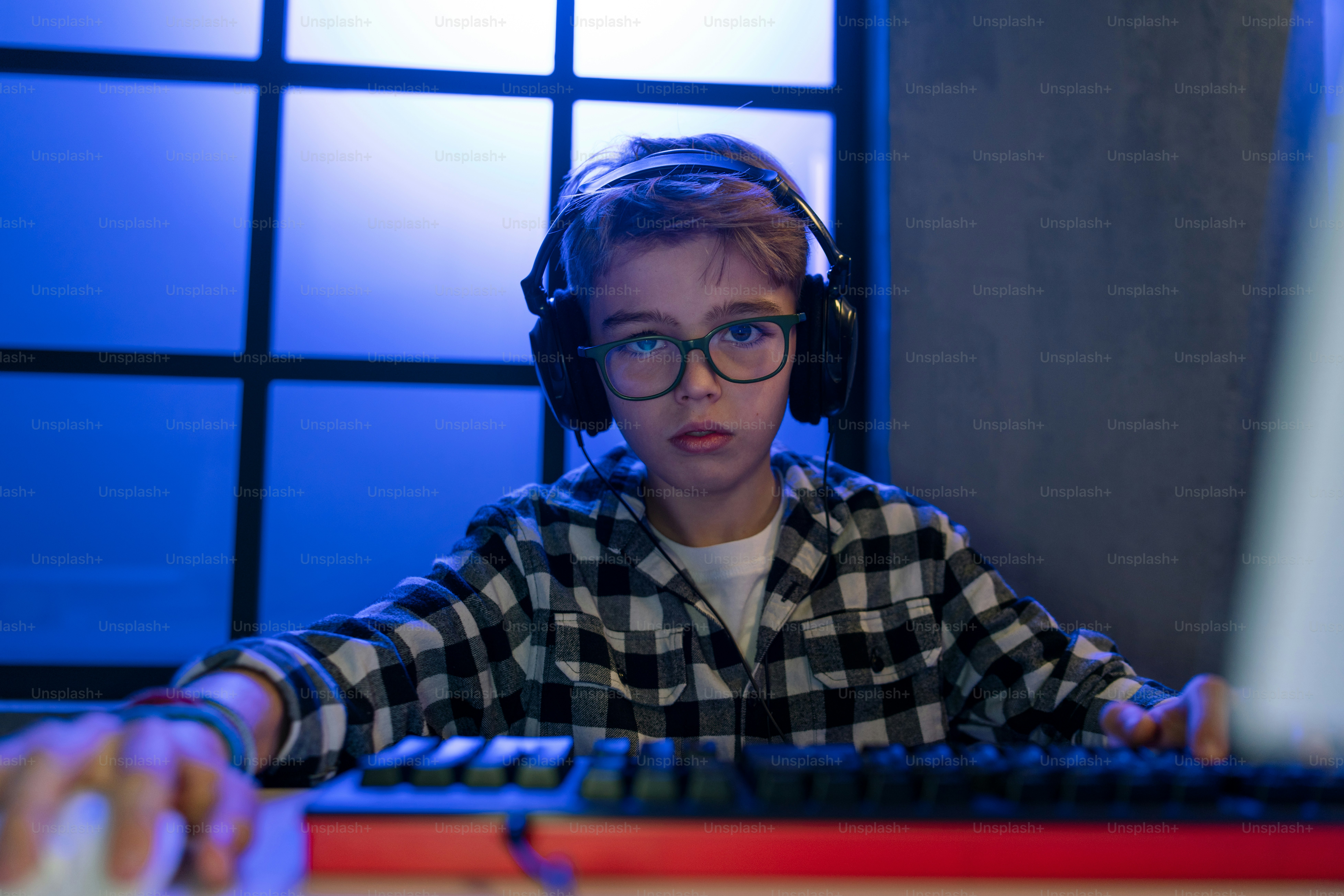 A young gamer boy with headphones playing computer video game. photo ...
