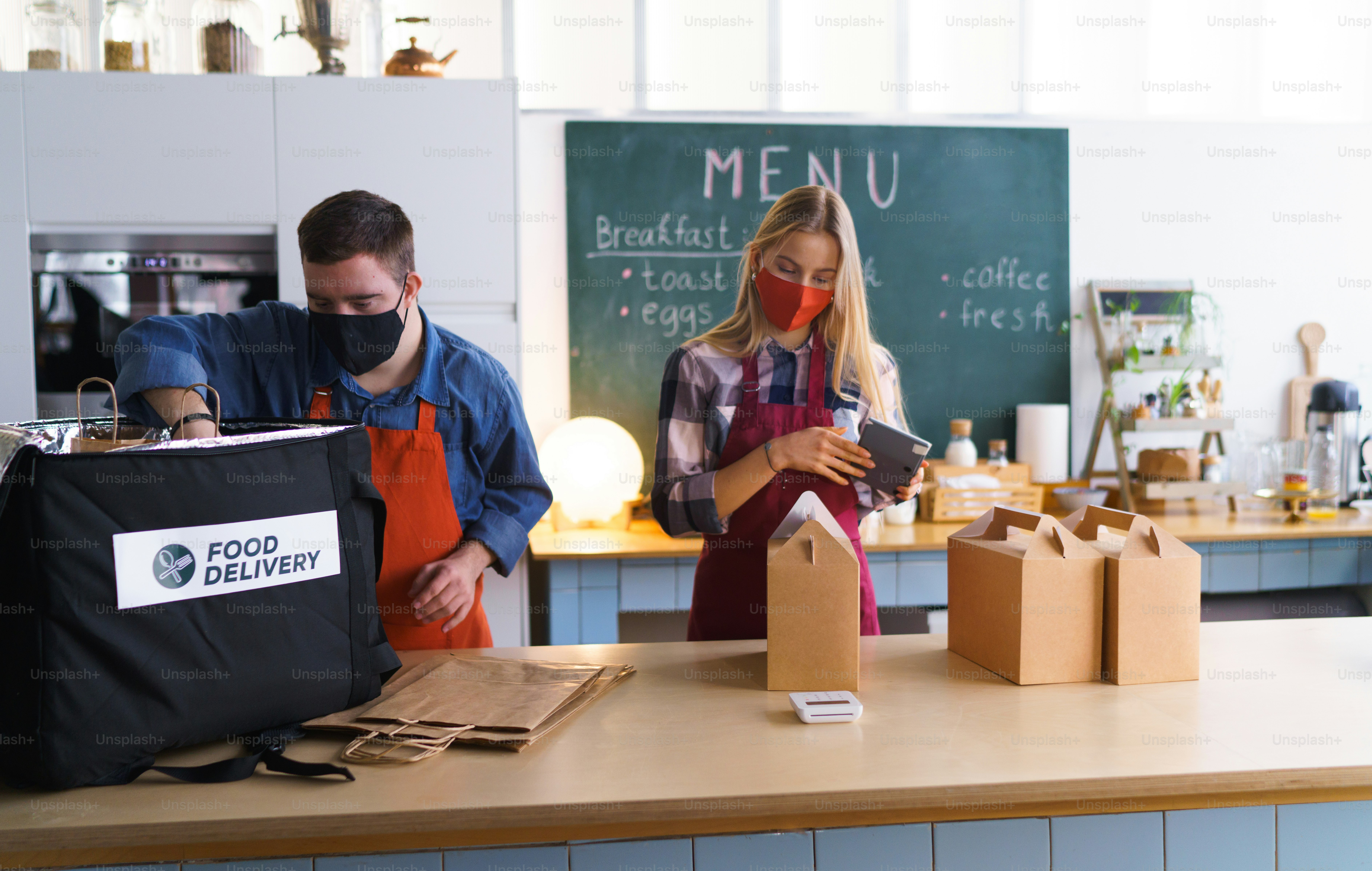Un joven camarero con síndrome de Down que trabaja con un colega en un restaurante de comida para llevar, concepto de inclusión social.