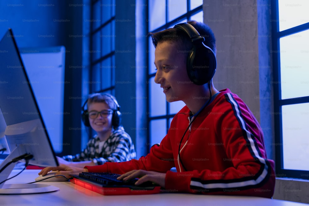 Young gamer boys with headphones playing a computer video game.