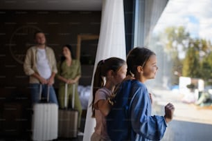 A happy young family with two children and luggage in room at luxury hotel, summer holiday.