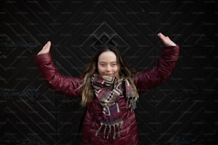 Eine glückliche junge Frau mit Down-Syndrom mit erhobenen Armen in der Stadt im Winter