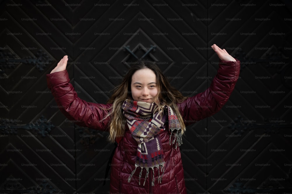 A happy young woman with Down syndrome with raised arms in town in winter
