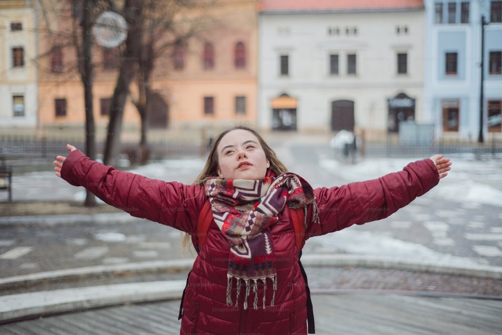 A happy young woman with Down syndrome with open arms in town in winter