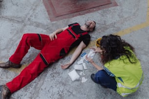 A woman is helping her colleague after accident in factory. First aid support on workplace concept.