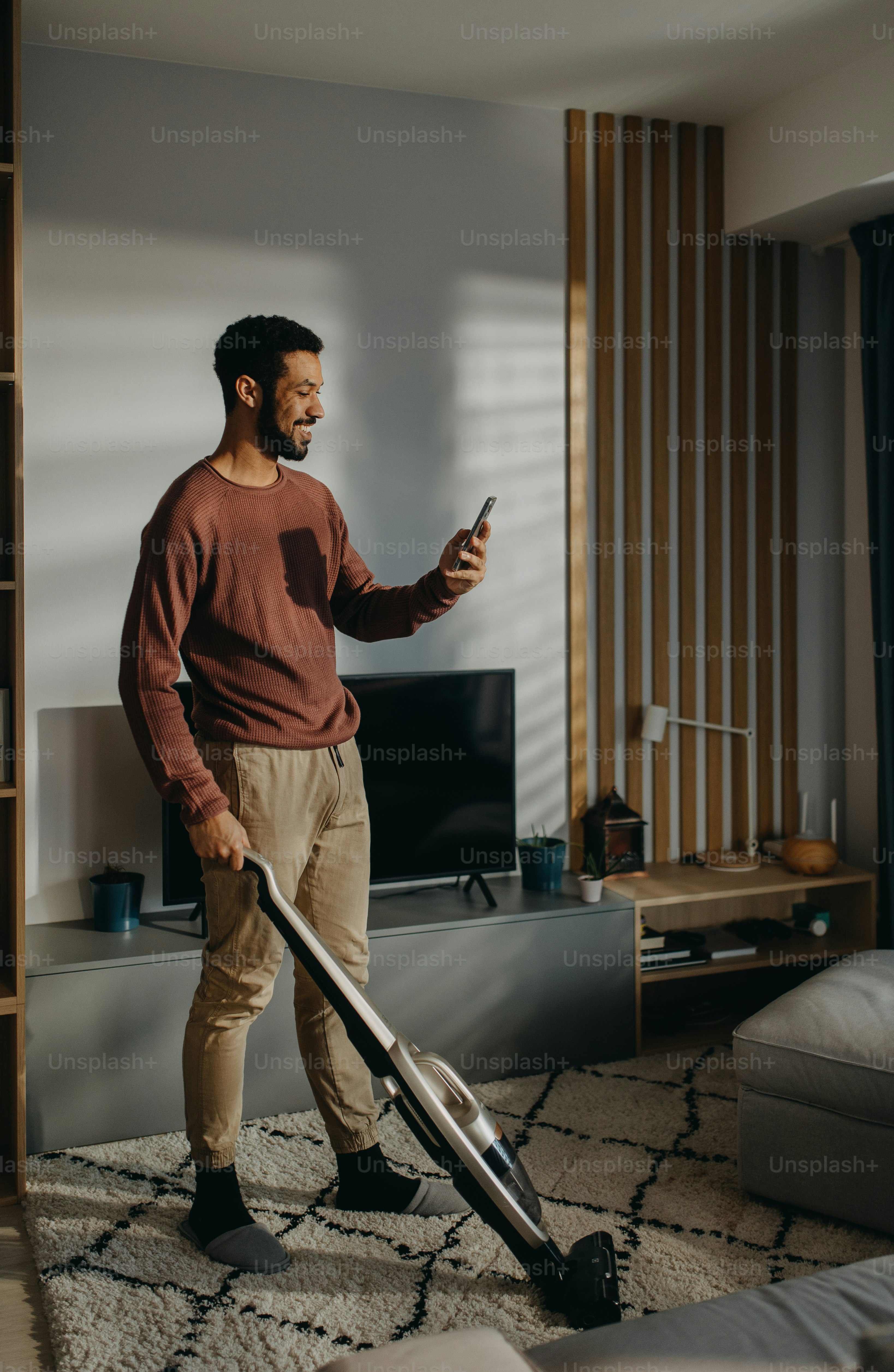 A young man vacuum cleaning carpet in living room photo – Cleaning ...