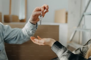 Un jeune couple heureux qui achète sa nouvelle maison et reçoit les clés d’un agent immobilier