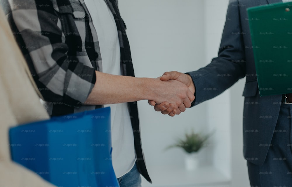 A close-up of young couple shaking hands with real estate agent when buying their new home.