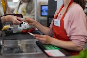 Cose-up d’une femme donnant de l’argent à un vendeur dans un supermarché