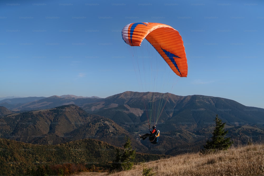 Paragliders flying in a blue sky with mountain in background.