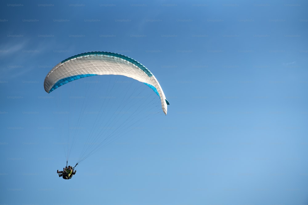 Ein Gleitschirm am blauen Himmel. Der Sportler fliegt auf einem Gleitschirm.