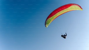 A paraglider in the blue sky. The sportsman flying on a paraglider.