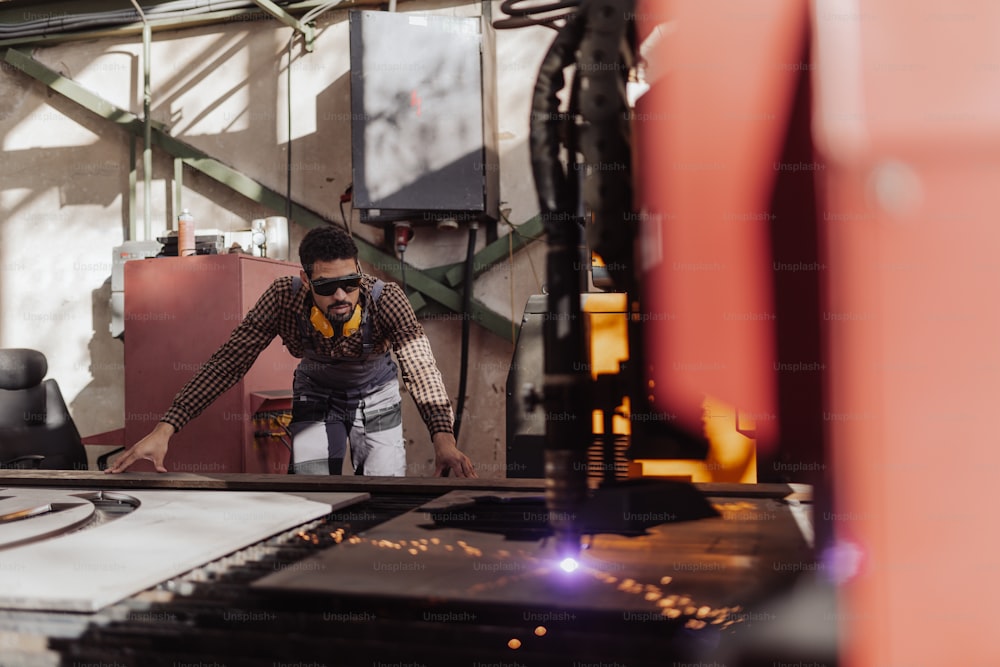 Un uomo che lavora sulla taglierina laser del metallo, tecnologia moderna in corso presso l'impianto di produzione della lavorazione dei metalli.