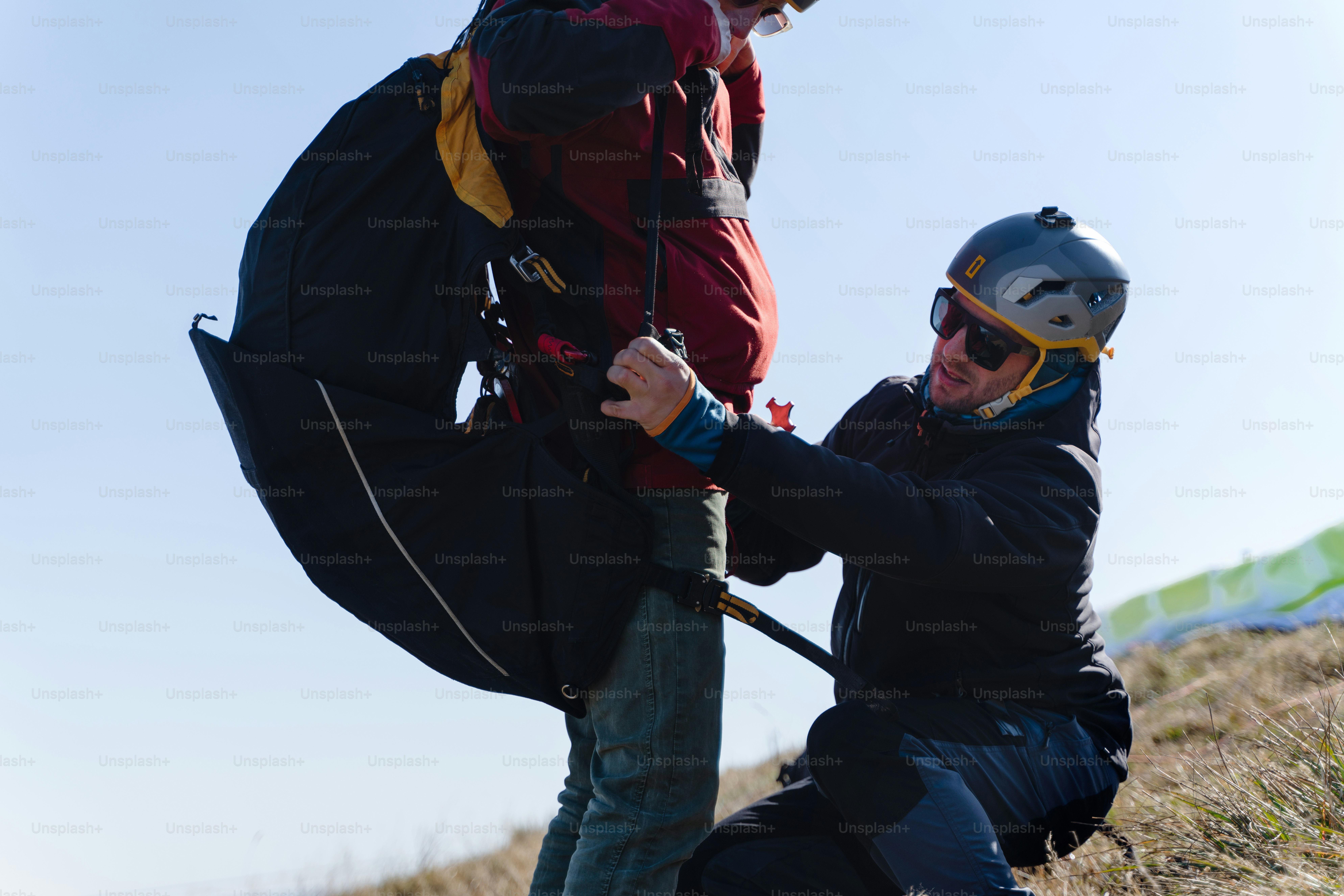 A man helping paragliding pilot to prepare for flight. photo ...