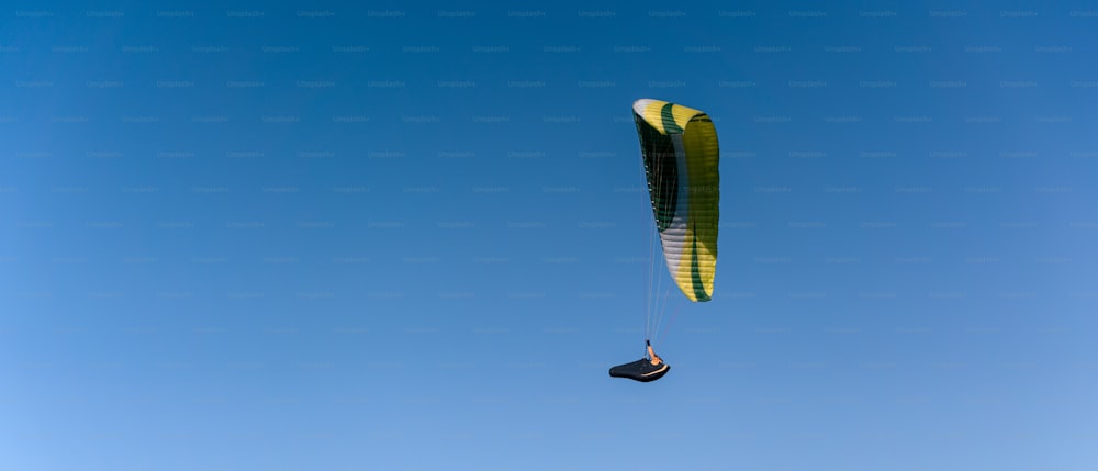 Ein Gleitschirm am blauen Himmel. Der Sportler fliegt auf einem Gleitschirm.