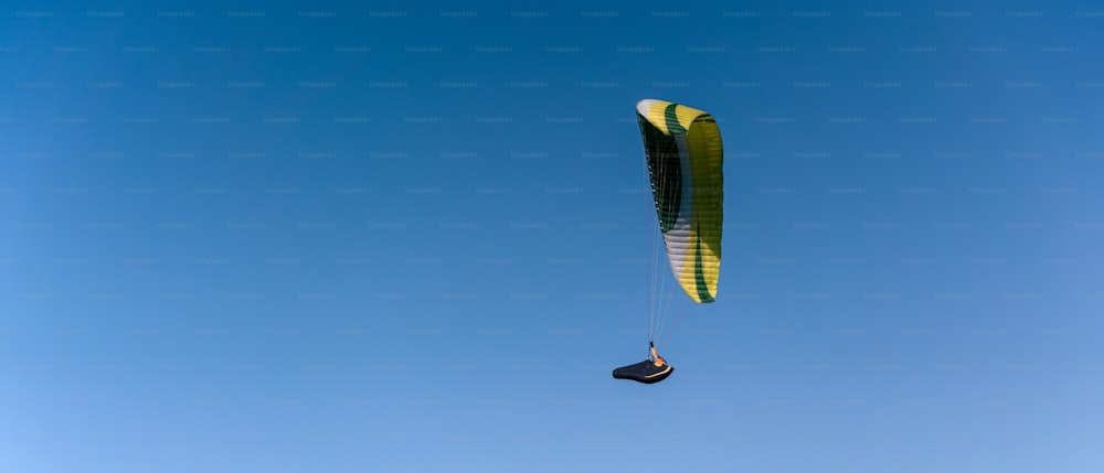 A paraglider in the blue sky. The sportsman flying on a paraglider.