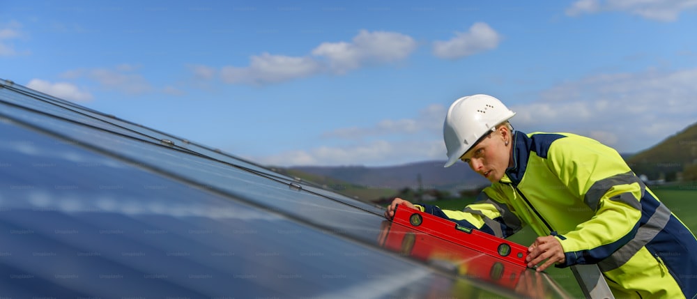 A woman engineer installing a solar photovoltaic panels on roof, alternative energy concept.