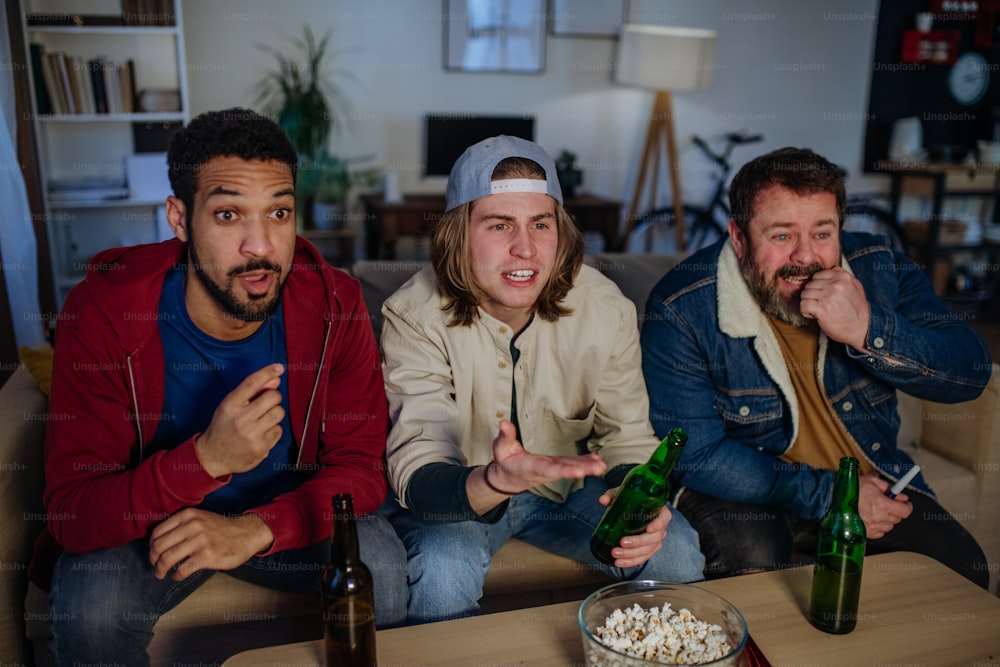 Nervous football fans friends watching live soccer match on a TV at home