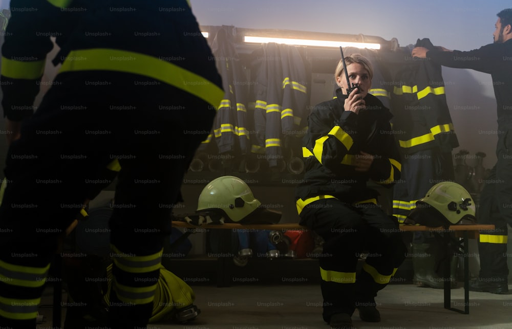 Bomberos ocupados, hombres y mujeres, preparándose para una acción en el interior de la estación de bomberos