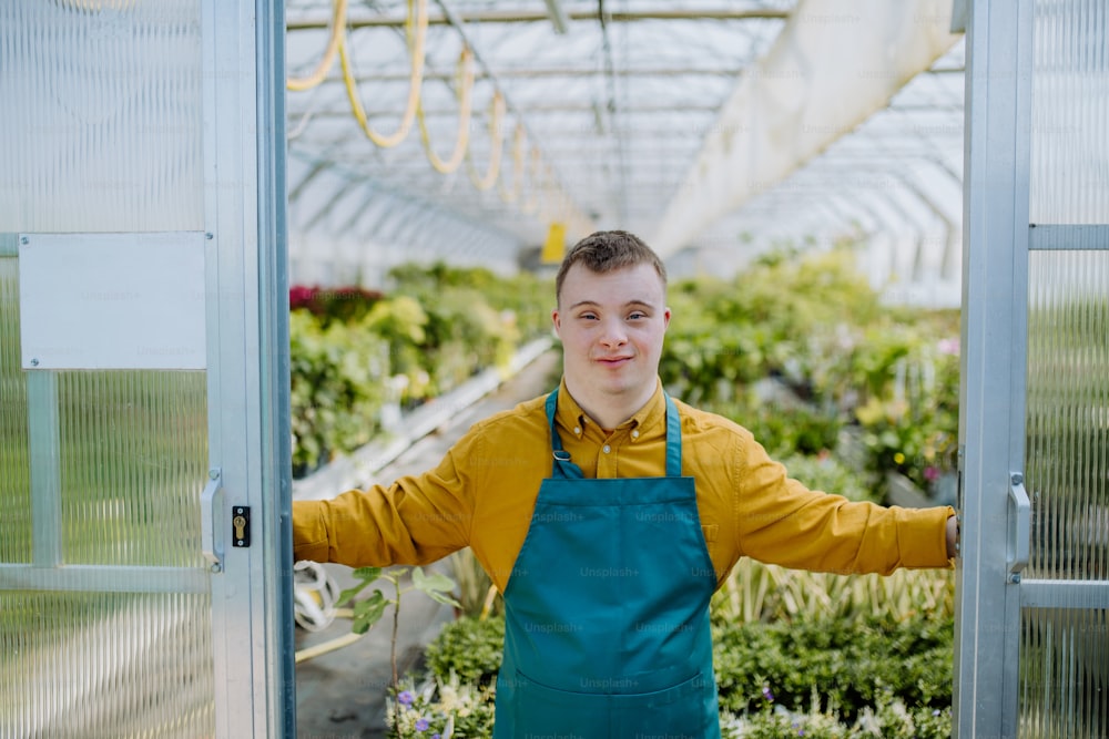 Um jovem funcionário com síndrome de Down trabalhando no centro de jardinagem, olhando para a câmera.