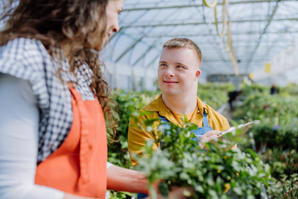 Une fleuriste expérimentée qui aide une jeune employée atteinte du syndrome de Down dans une jardinerie.
