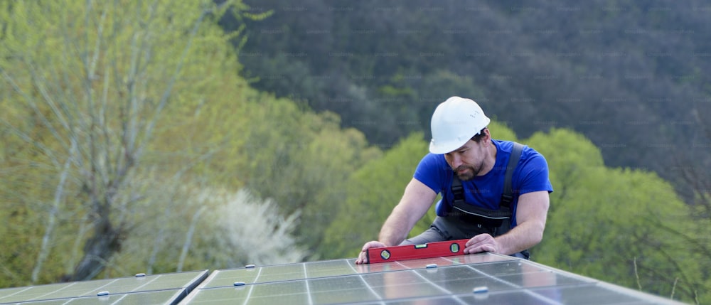 지붕에 태양광 패널을 설치하는 남자 노동자, 대체 에너지 개념.