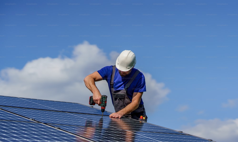 Um trabalhador que instala painéis solares fotovoltaicos no telhado, conceito de energia alternativa.