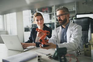 Robotics engineers working on a laptop and desinging modern robotic arm in laboratory.