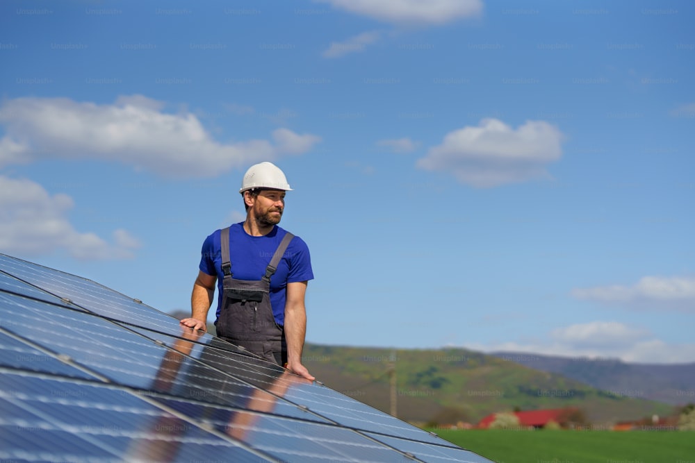 지붕에 태양광 패널을 설치하는 남자 노동자, 대체 에너지 개념.
