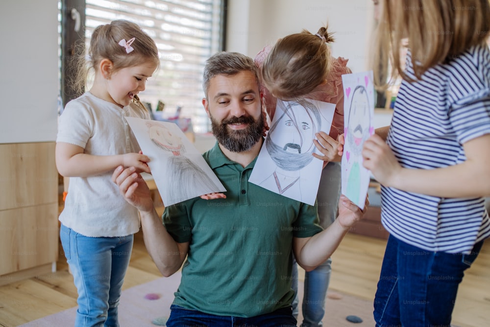 Um pai de três filhas pequenas recebendo desenhos deles em casa.