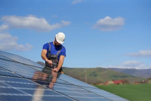 A man worker installing solar photovoltaic panels on roof, alternative energy concept.