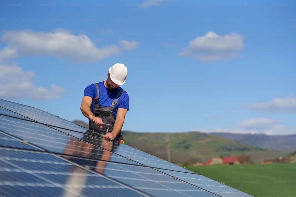 屋根に太陽光発電パネルを設置する男性作業員、代替エネルギーのコンセプト。