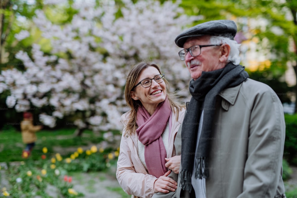 Un uomo anziano felice con la figlia adulta all'aperto su una passeggiata nel parco.