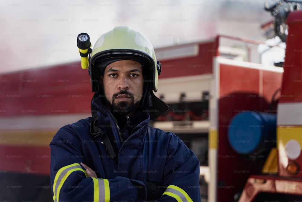 A serious young African-american firefighter man with fire truck and smoke in background.