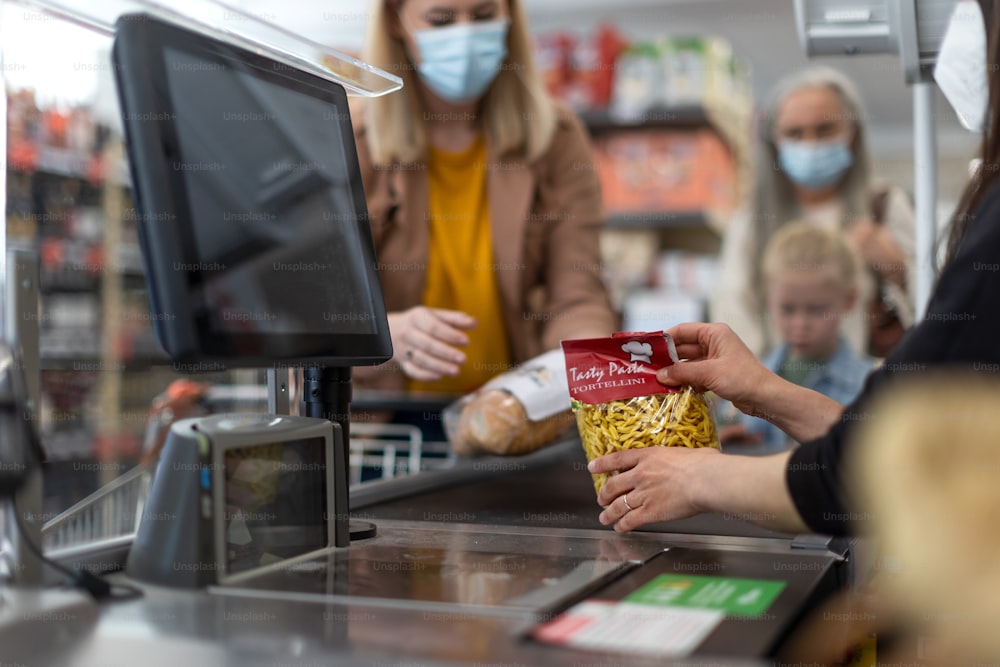 A checkout counter hands of the cashier scans groceries in supermarket.