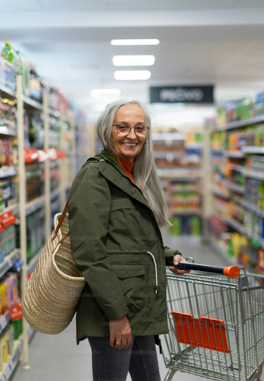 Una mujer mayor de pie y comprando en el supermercado.
