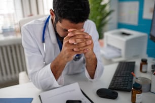 Ein depressiver junger Arzt mit Kopfschmerzen sitzt in seinem Büro