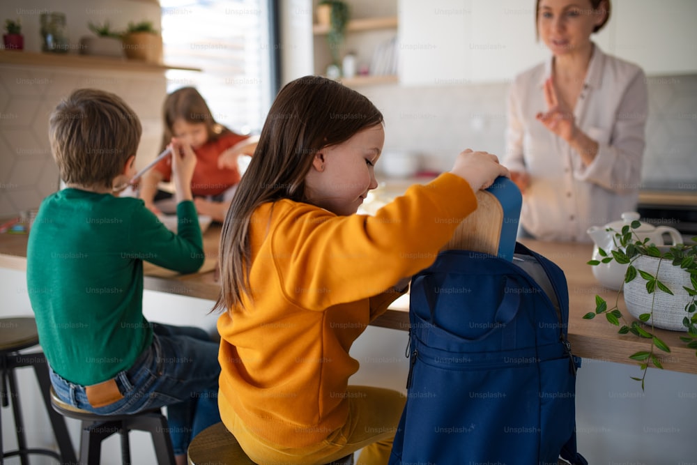 Ein kleines Mädchen, das zu Hause in der Küche eine Lunchbox für den Rucksack packt.