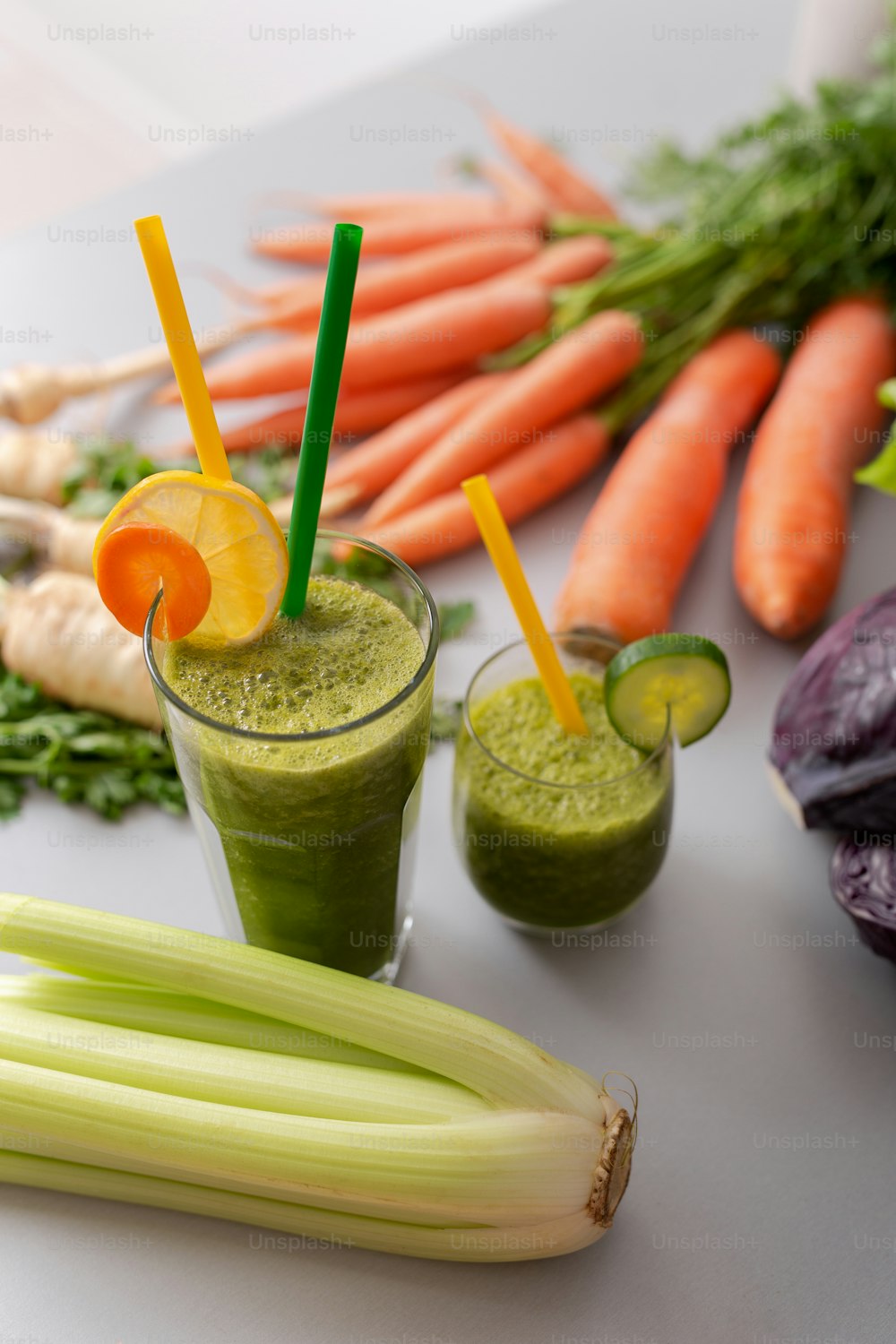 Ein grüner Smoothie im Glas mit Stroh und Gurke und Gemüse im Hintergrund, Detox, veganes, vegetarisches gesundes Gemüsegetränk