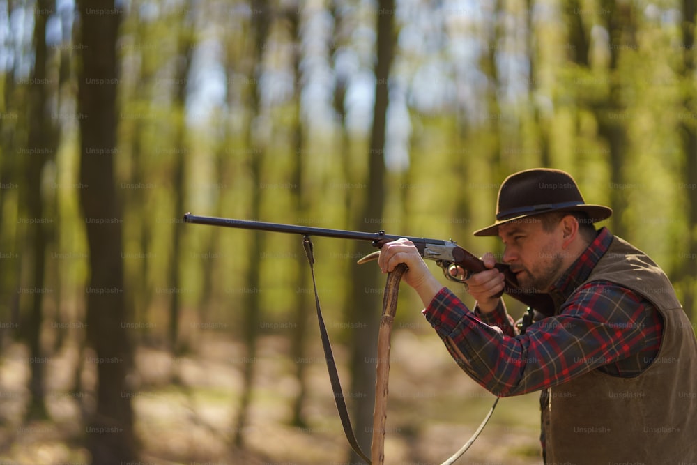 Un chasseur visant avec un fusil sur une proie dans la forêt.