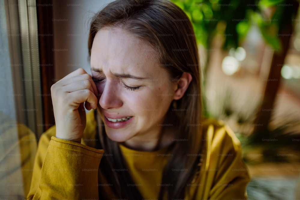 うつ病に苦しんで家で泣いている女性。