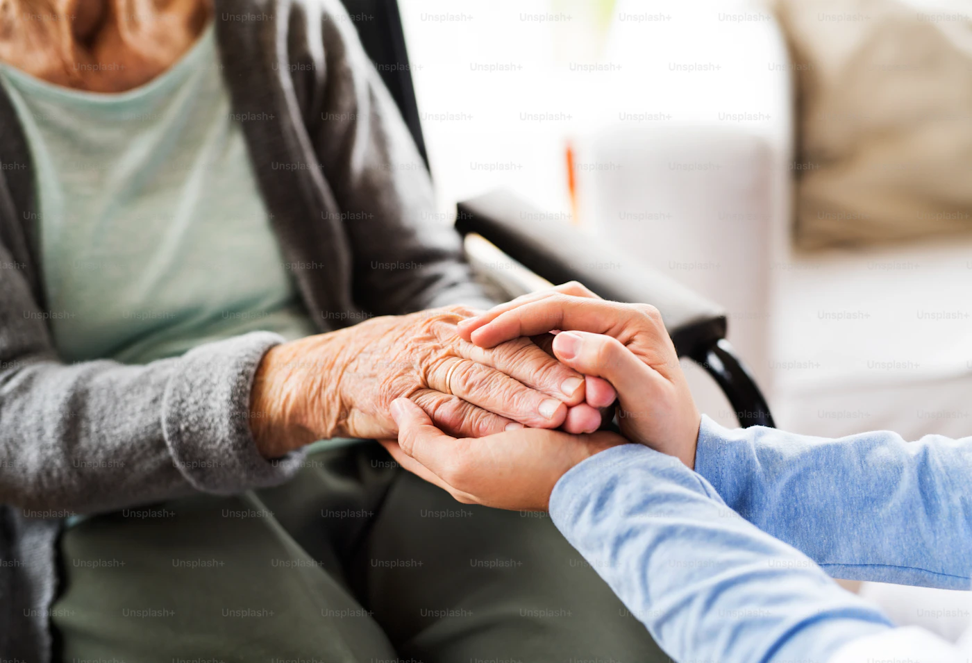 Caregiver holding an elderly resident's hand in a nursing home setting