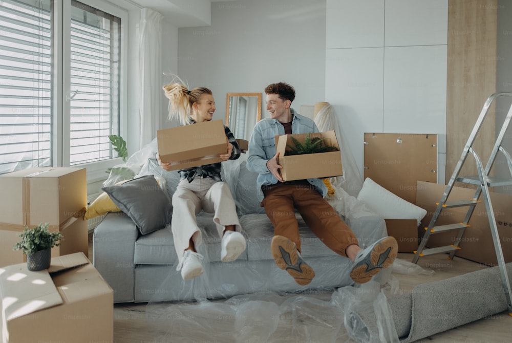 Una alegre pareja joven en su nuevo apartamento, cargando cajas. Concepción de la mudanza.