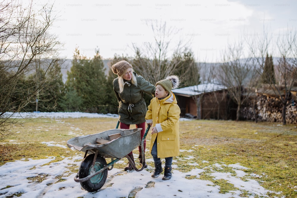 Un garçon trisomique travaillant dans le jardin en hiver avec sa grand-mère.