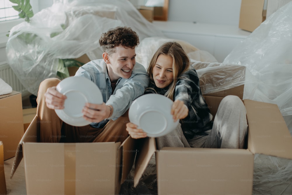 A cheerful young couple in their new apartment, having fun when unpacking. Conception of moving.